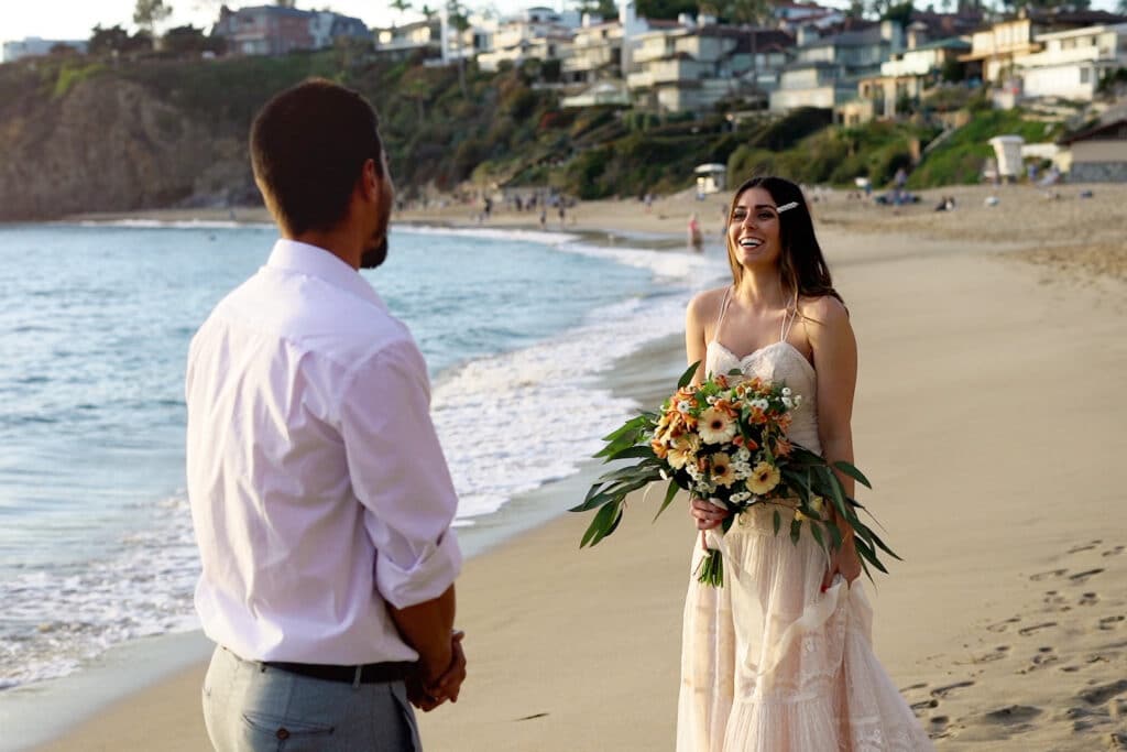 bride smiling at groom on beach at wedding with tropical bouquet by Lexi Rabelo Films