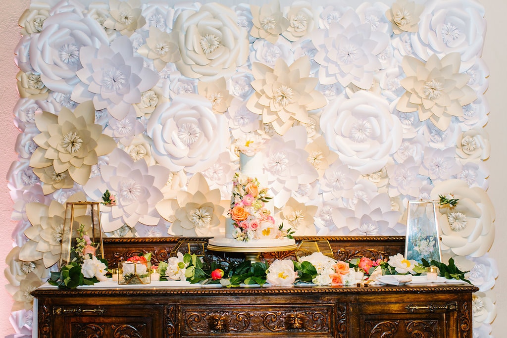 White floral wall behind wedding cake buffet table by Petal & Grain