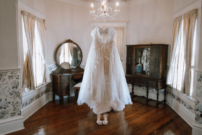 Beautiful bridal suite adorned with vintage cabinets. The bride's lace dress is hanging under a chandelier.