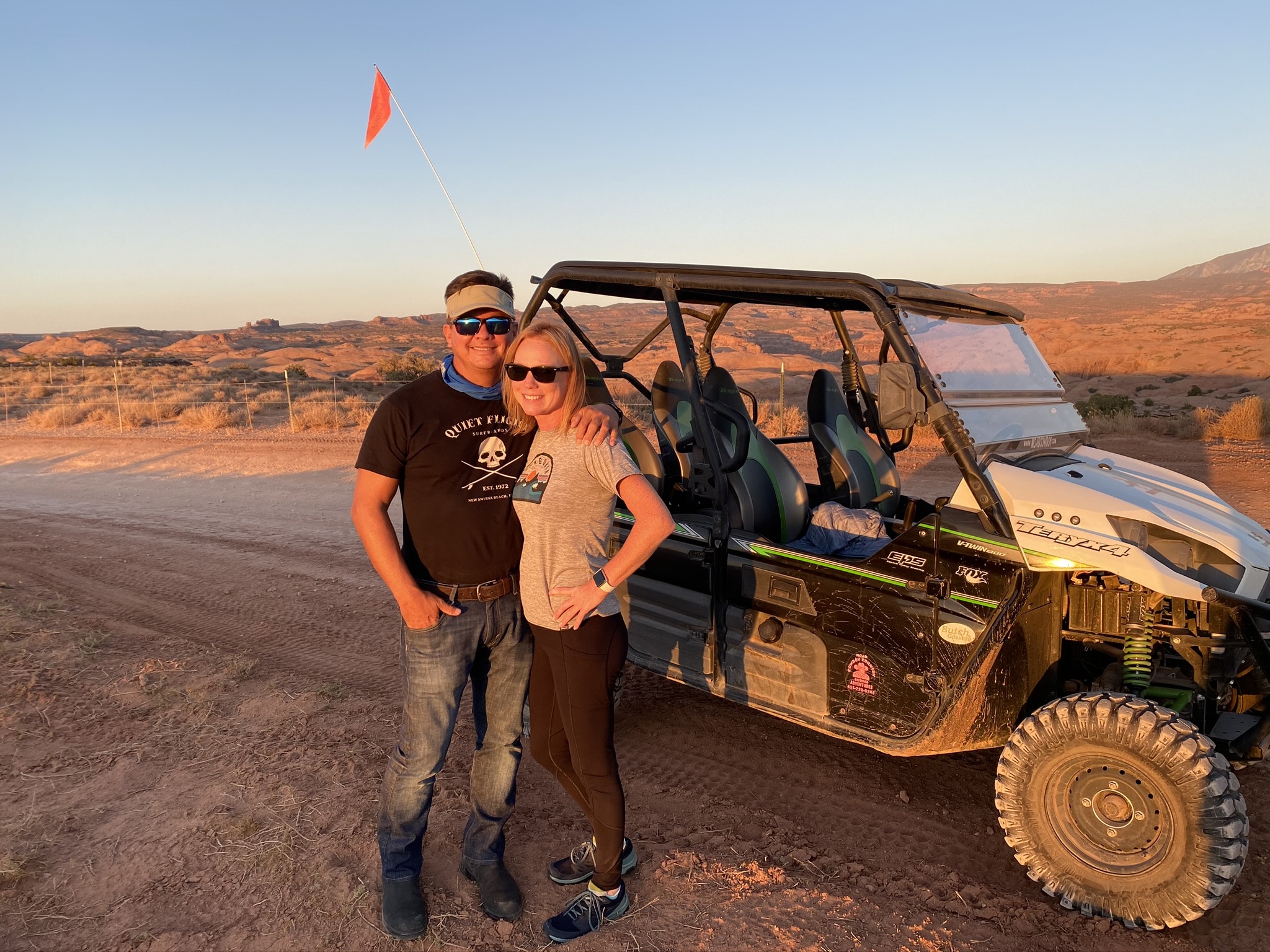 Man and woman in front of a 4x4 truck in the dirt