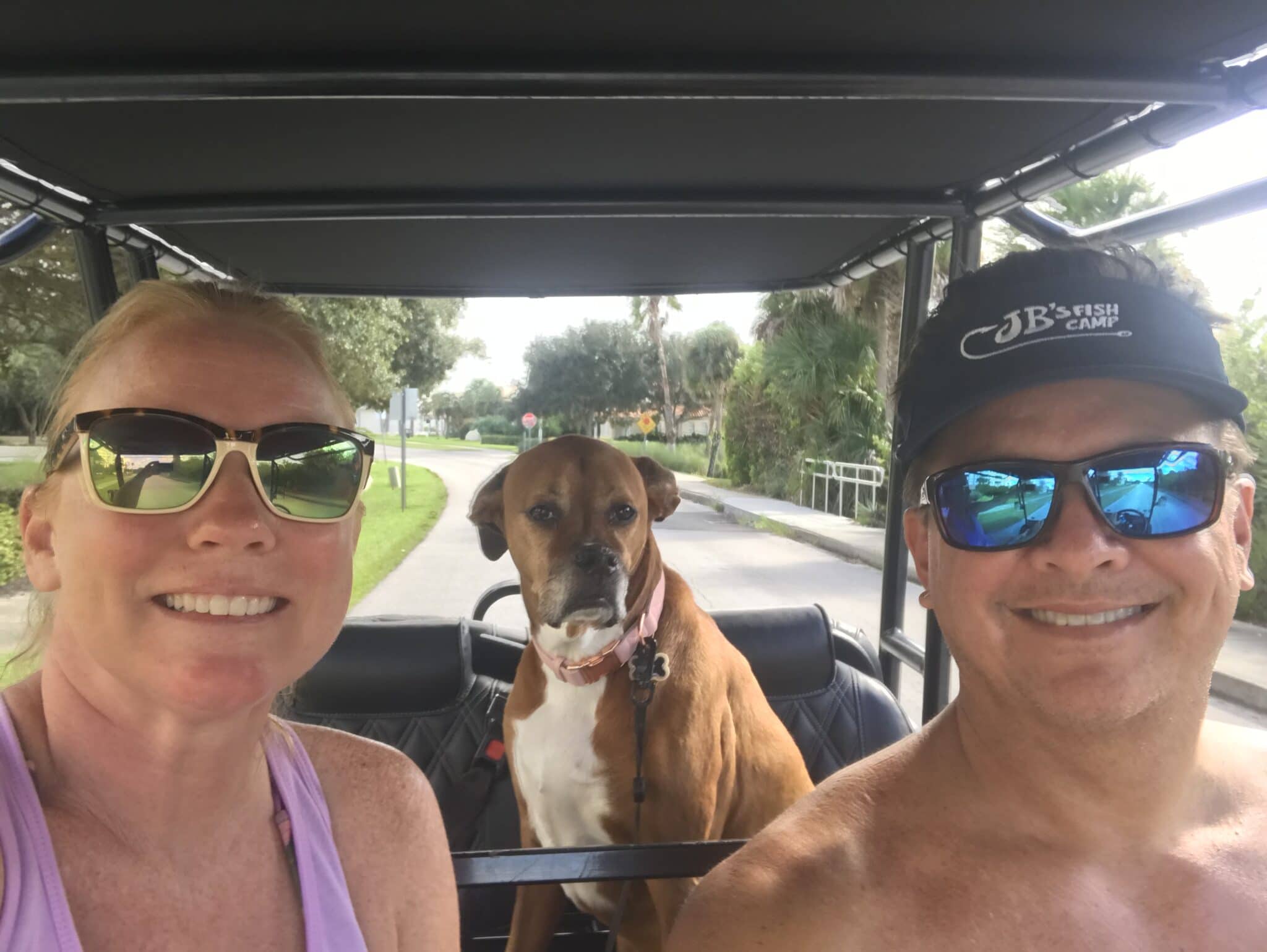 couple in golf cart with dog as a passenger