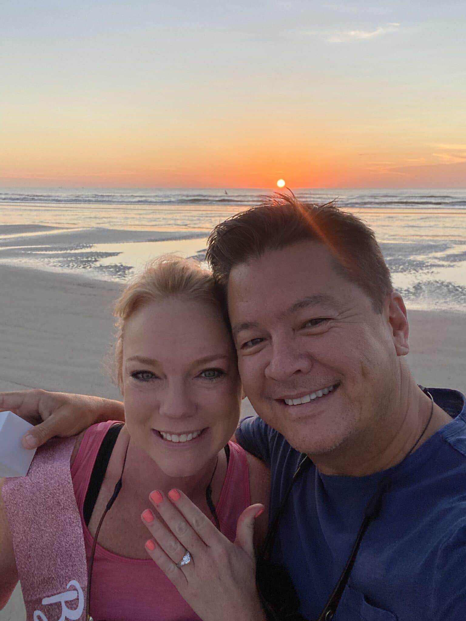 couple celebrating marriage proposal on beach
