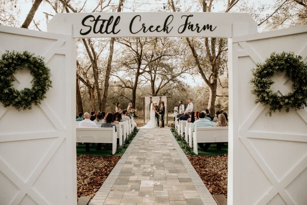 outdoors, white wooden doors, a wreath on each door, stone walkway, white benches for guests, Still Creek Farm, sign, Central, FL
