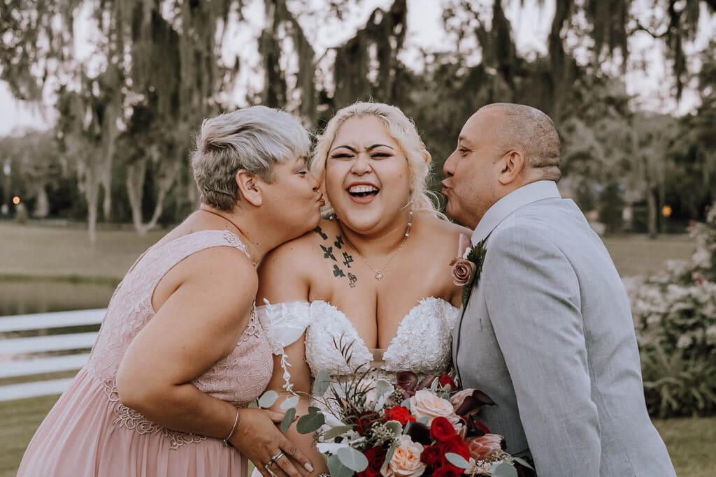 Parents of the bride kissing her cheeks