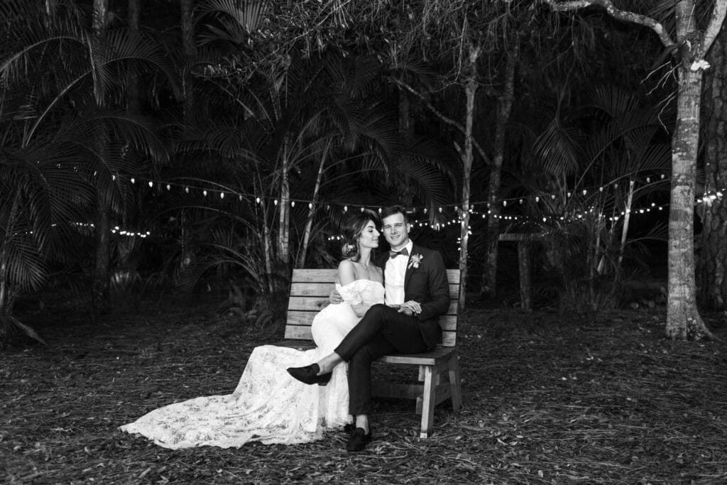 bride and groom in garden on a bench in black and white photo