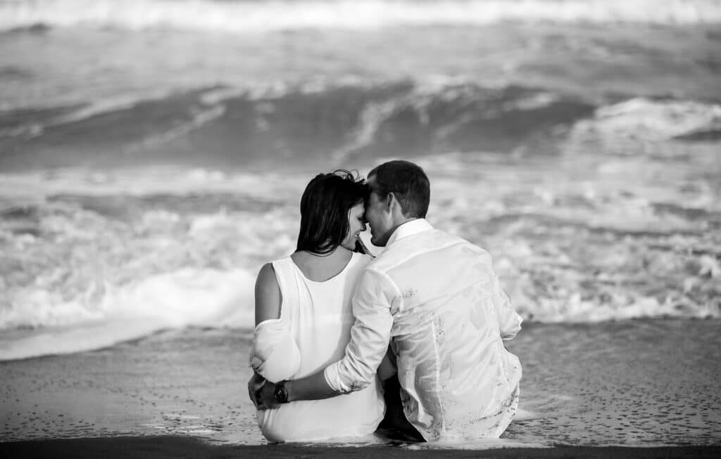 black and white photo of couple sitting at the beach photographed by Sterling Photography International
