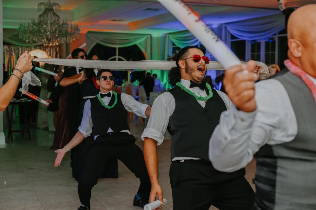 groomsmen with sunglasses and leis dancing the limbo photo by Carolina Irais Photography