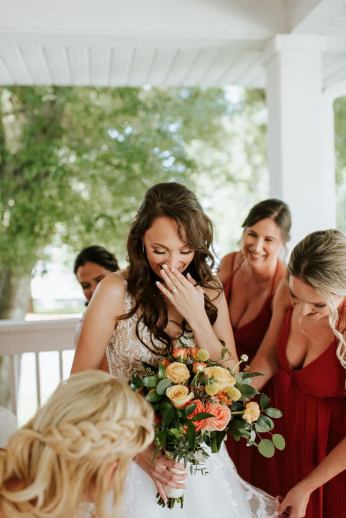 bride with bridesmaids looking at her bouquet by Joanna Moore Photography