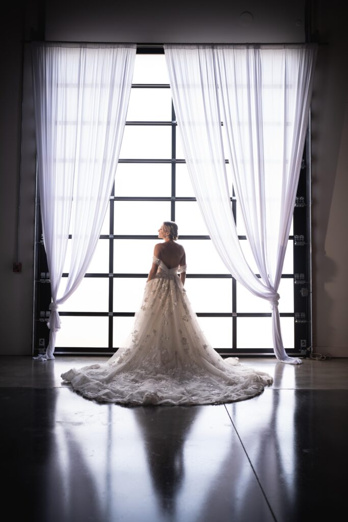 bride in bridal gown draped behind her silhouetted against large window with white draping at D'Space Orlando