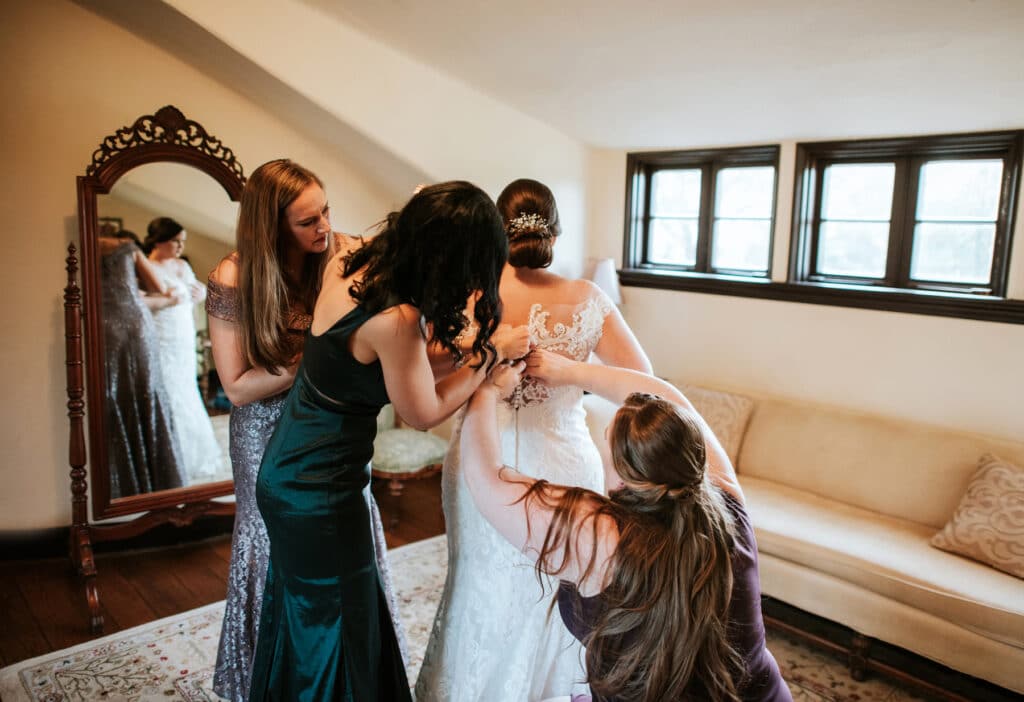final preparations of bride getting ready with bridesmaids by Joanna Moore Photography