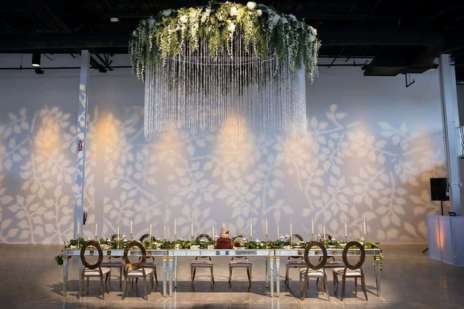 wedding reception table with extra large chandelier covered in greenery by Puff 'n Stuff Catering