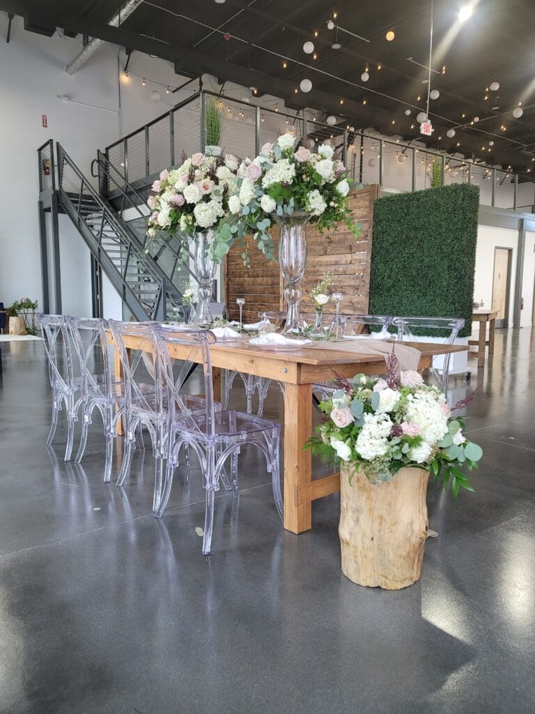 rustic table setup with plexiglass chairs and tall greenery at D'Space Orlando