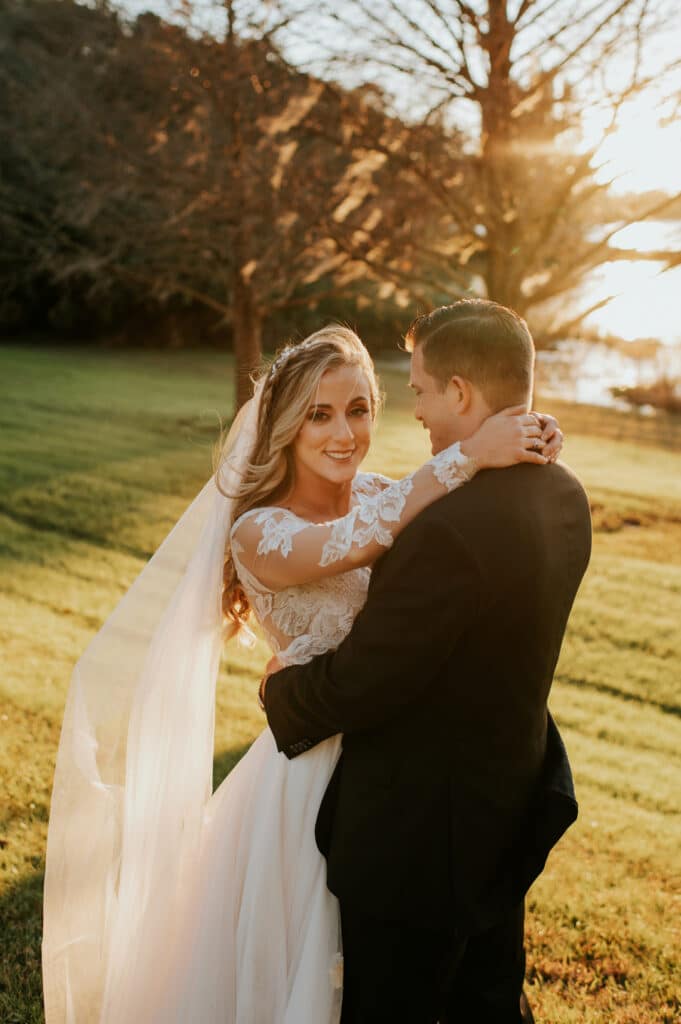 bride and groom embracing at sunset by Joanna Moore Photography