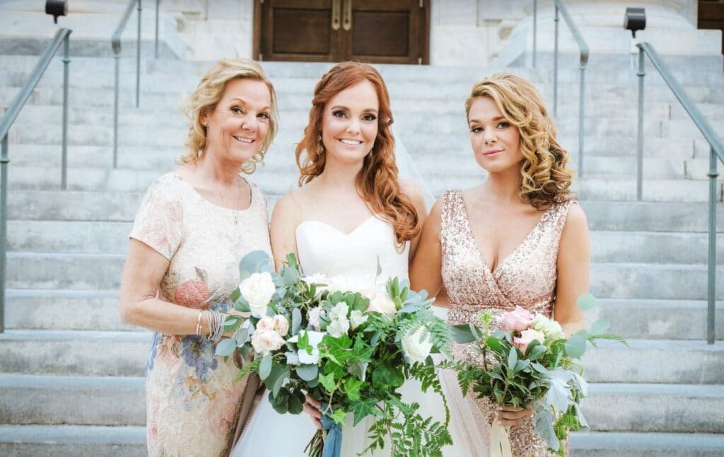 three women at foot of steps in wedding clothes with hair and make-up by Hair Logic Beauty Bar
