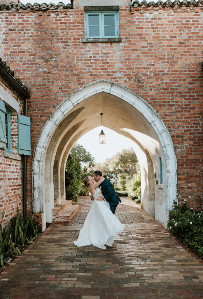 groom dipping bride for a kiss under brick arches photo by Joanna Moore Photography in Orlando, FL