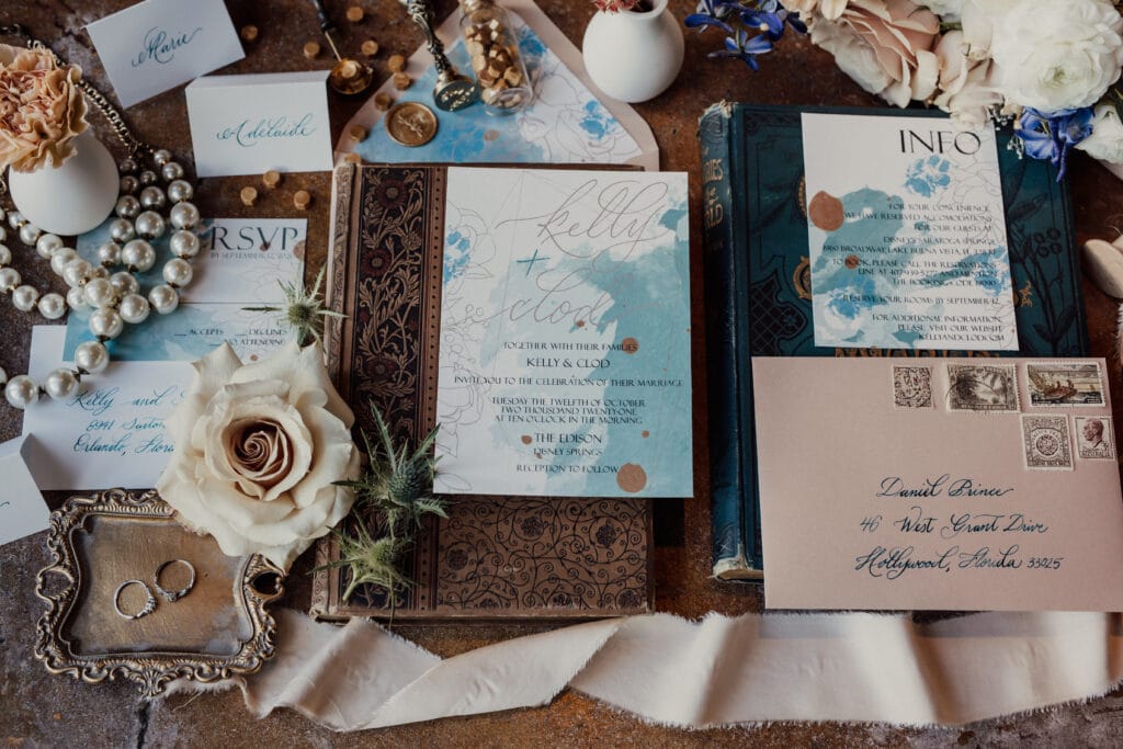 Invitation arrangement with flowers, rings, and pearls.
