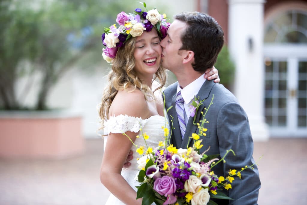 groom kissing bride with fresh flower headband and matching bouquet photographed by Sterling Photography International