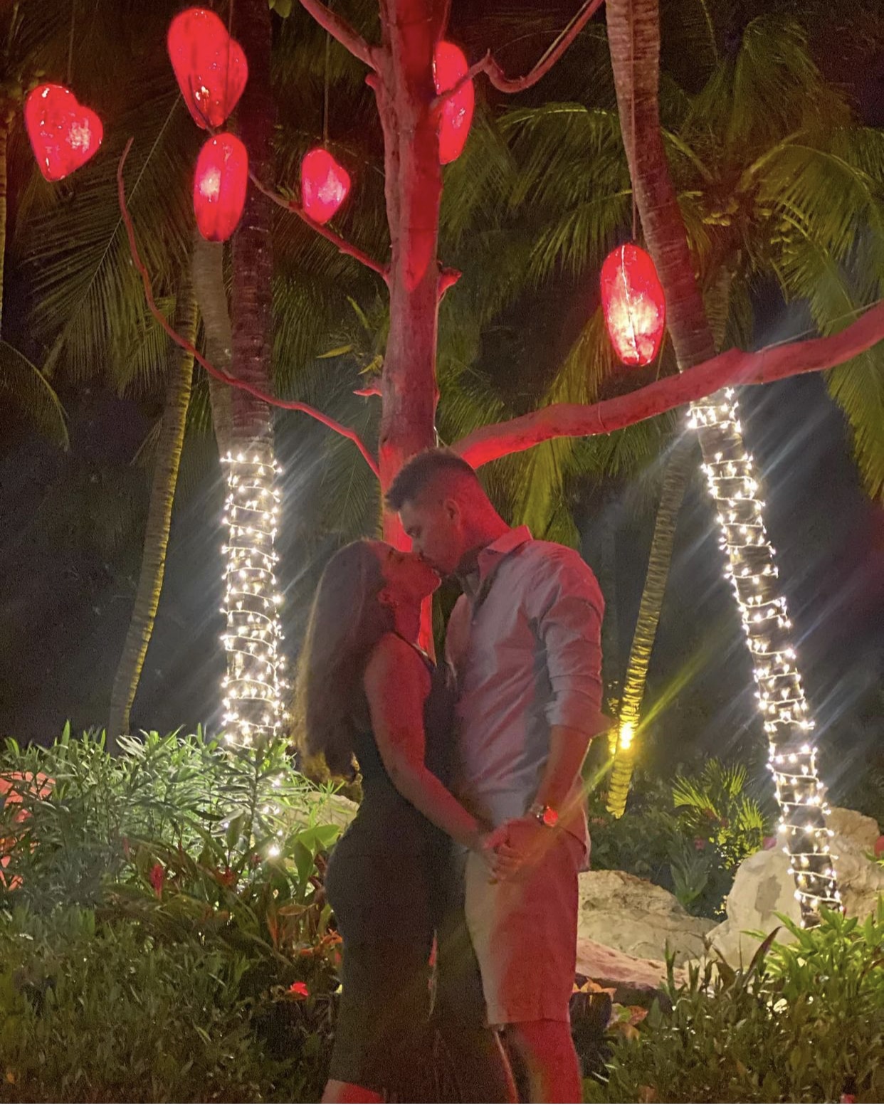 couple kissing under red lanterns at night in garden