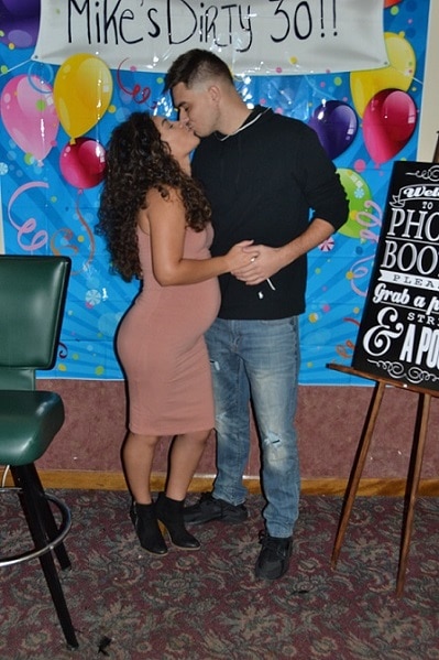 Pregnant woman and partner kissing at a birthday party