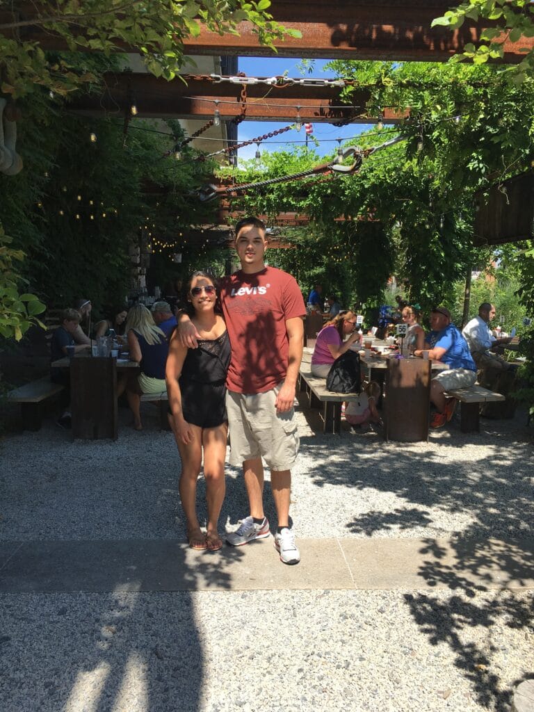 couple posing under wooden beams in outdoor courtyard