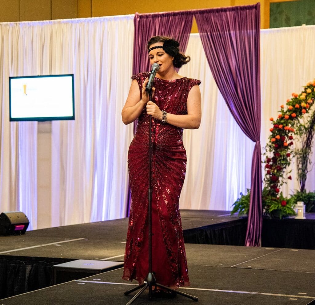 woman in burgundy sequined dress singing into microphone from Sol Rise Entertainment
