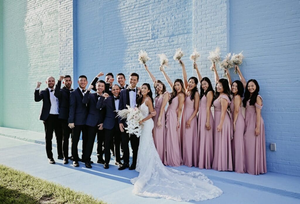 bride and groom against colorful wall with bridesmaids all in pink at Haus 820