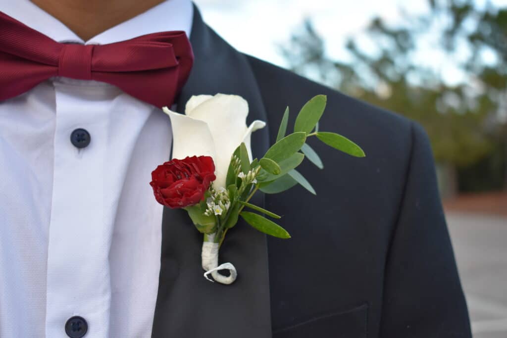 grooms boutonniere of white rose and red baby carnation by Stems in Bloom