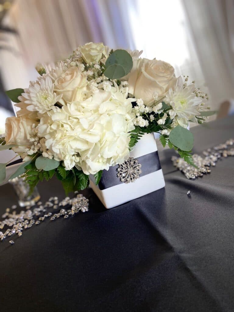 table centerpiece of white flowers with black and white table accents by Stems in Bloom