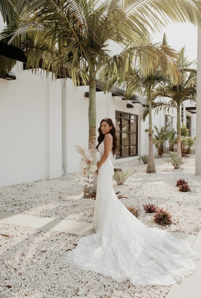 Bride outside white building with sand and palm trees at Haus 820