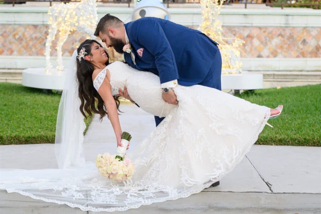 groom dipping his bride outside by a fountain by Bold Beautiful and Beyond weddings
