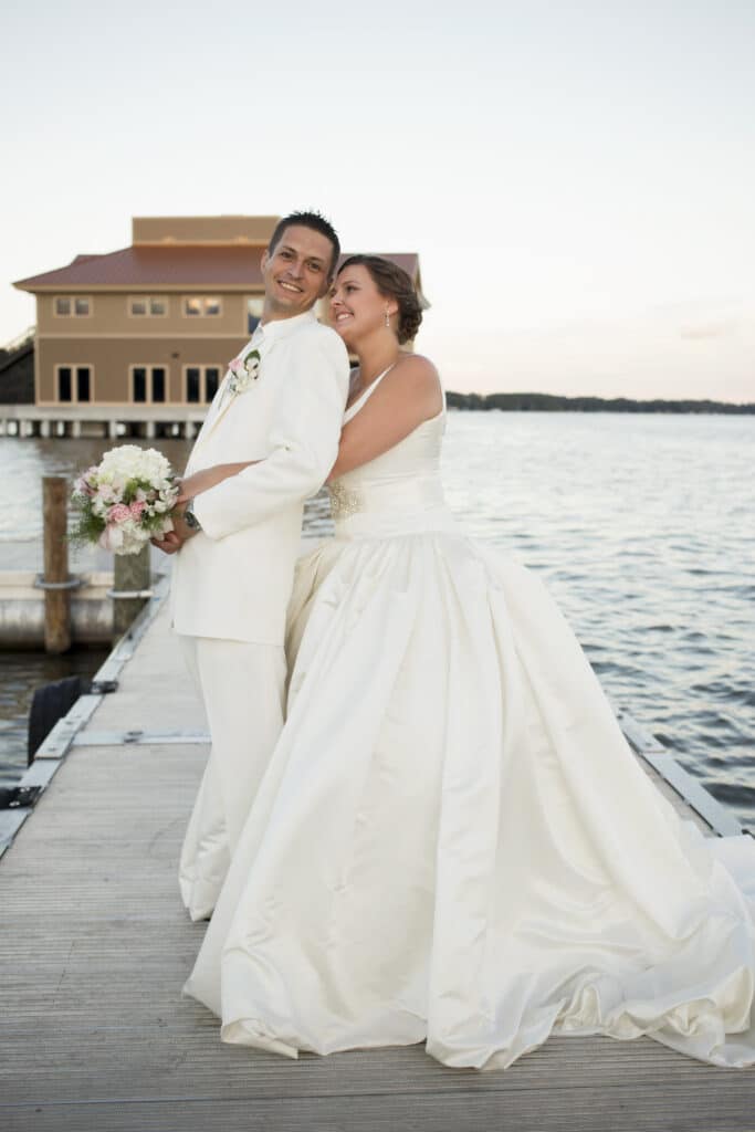 bride and groom embracing on a pier at sunset