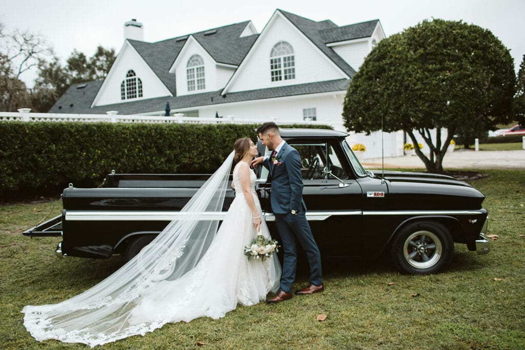 Bride and Groom in front of vintage black truck on front lawn at Bramble Tree Estate