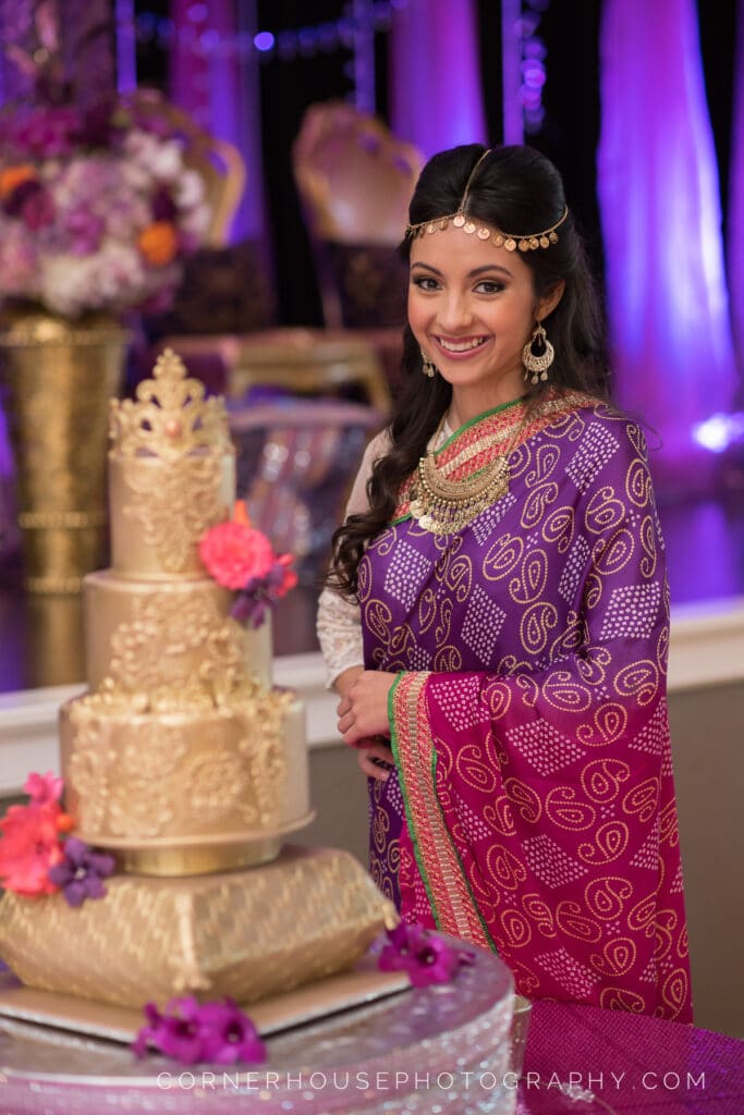 bride in colorful sari looking at elaborately decorated wedding cake