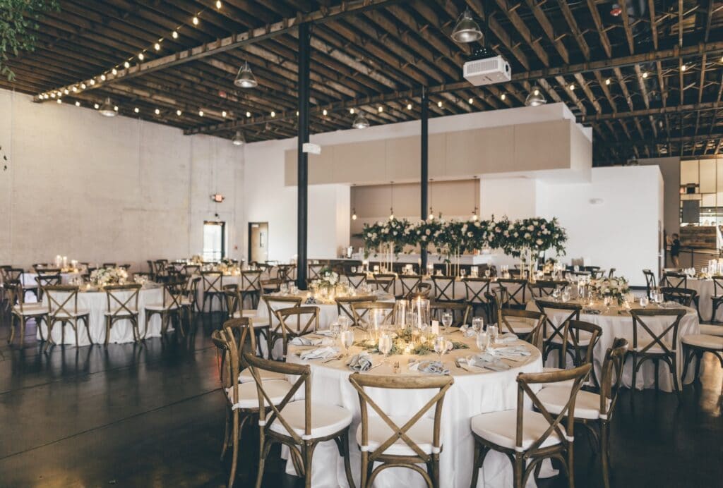 indoor venue with round tables and candle centerpieces under market lights at Haus 820