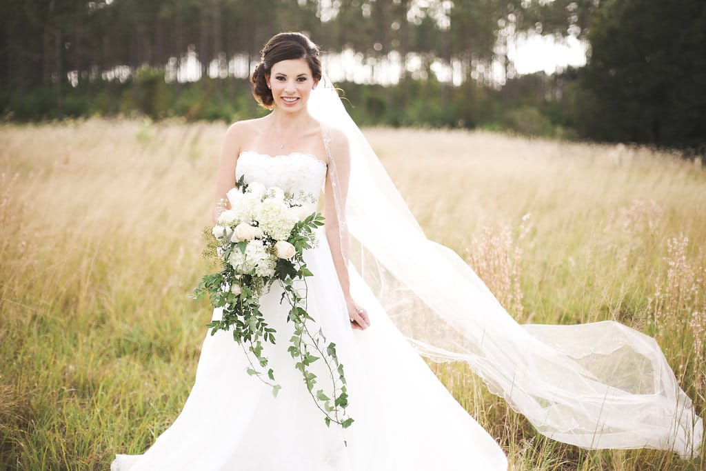 bride posing in a field by Bold Beautiful and Beyond weddings