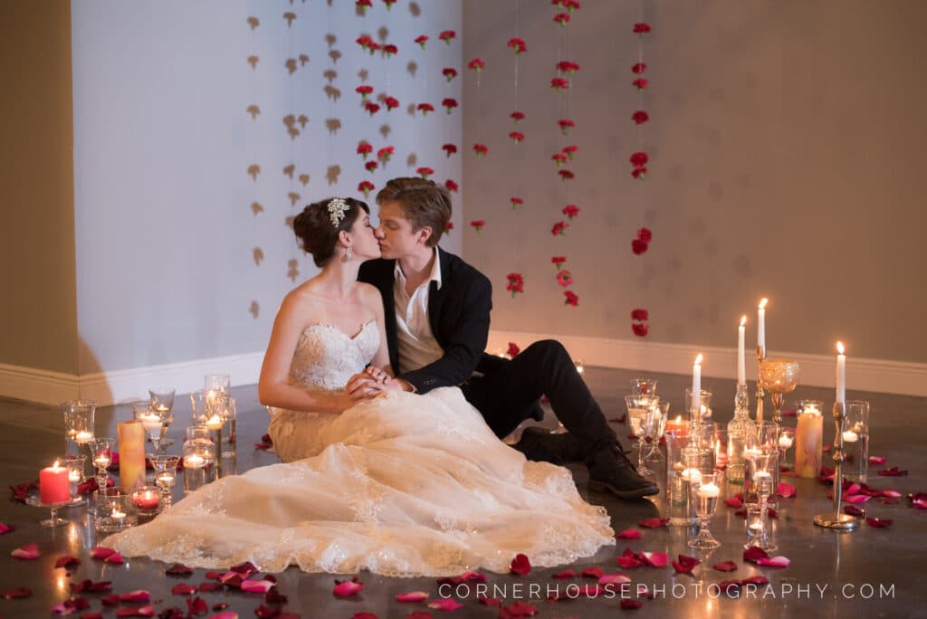 bride and groom sitting on floor kissing surrounded by candles