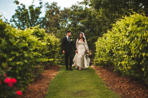 Bride and groom walking through the gardens at Bella Collina