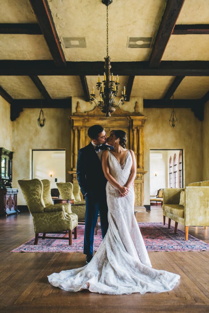 bride and groom kissing in room with wood beams photo by Rudy and Marta Photography