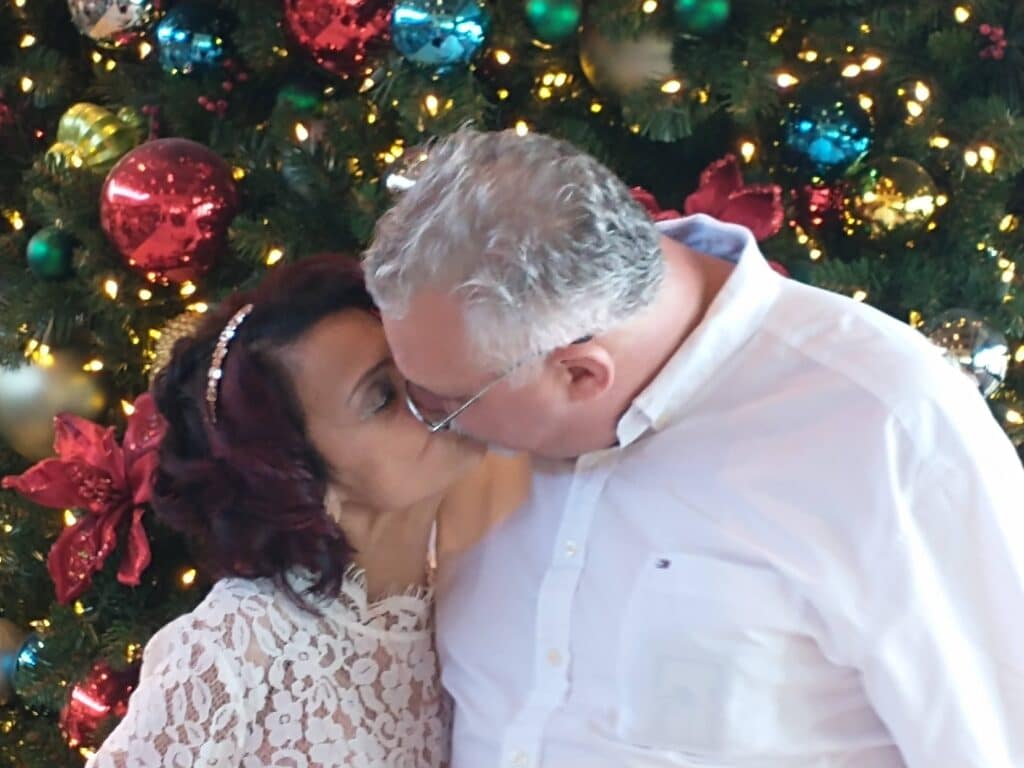 Bride and groom kissing in front of a Christmas tree