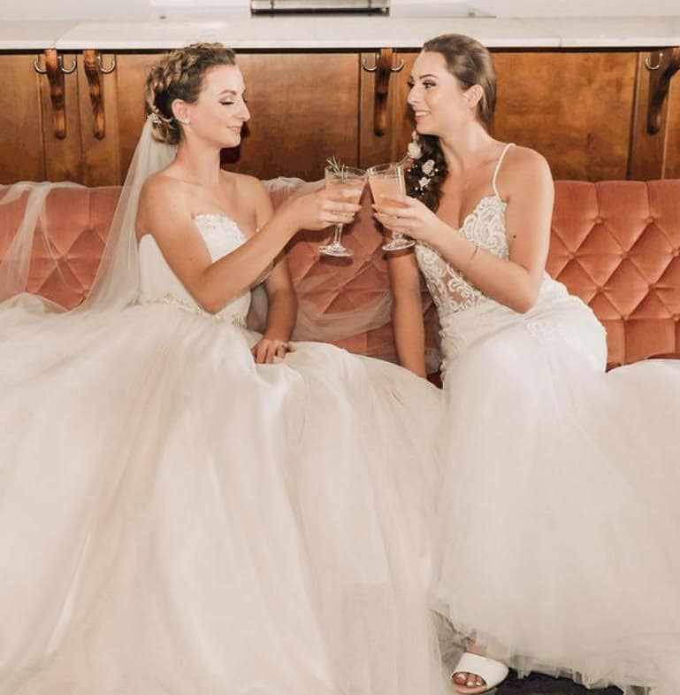 brides sharing a champagne toast with hair and make-up by Awe Glammed Up