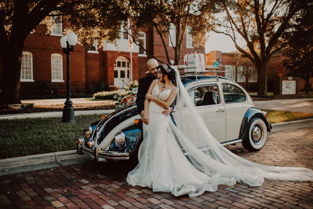 Bride and groom posing in front of an old Volkswagon Beetle