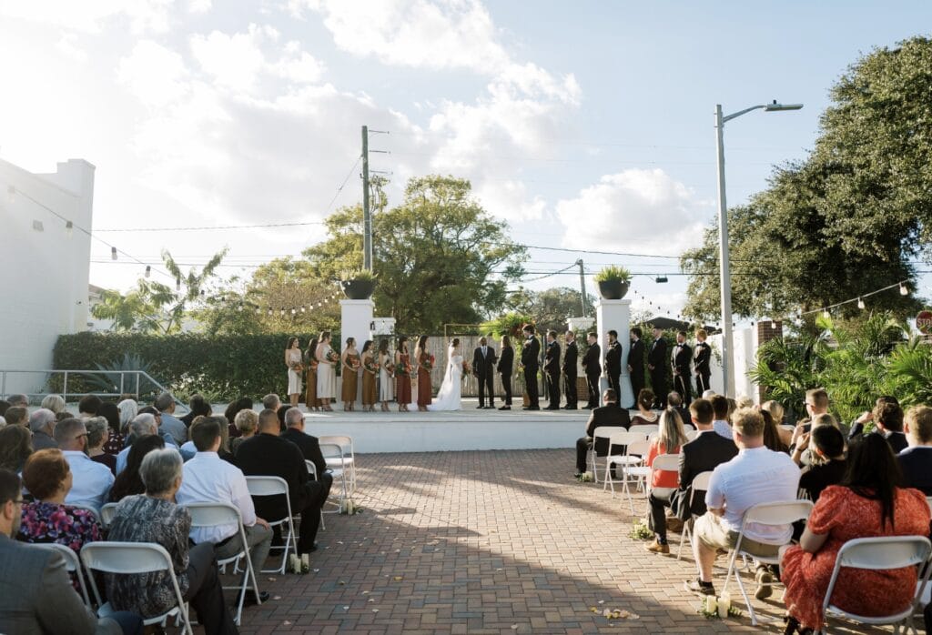 outdoor wedding ceremony with large wedding party and white pillars in the background at Haus 820