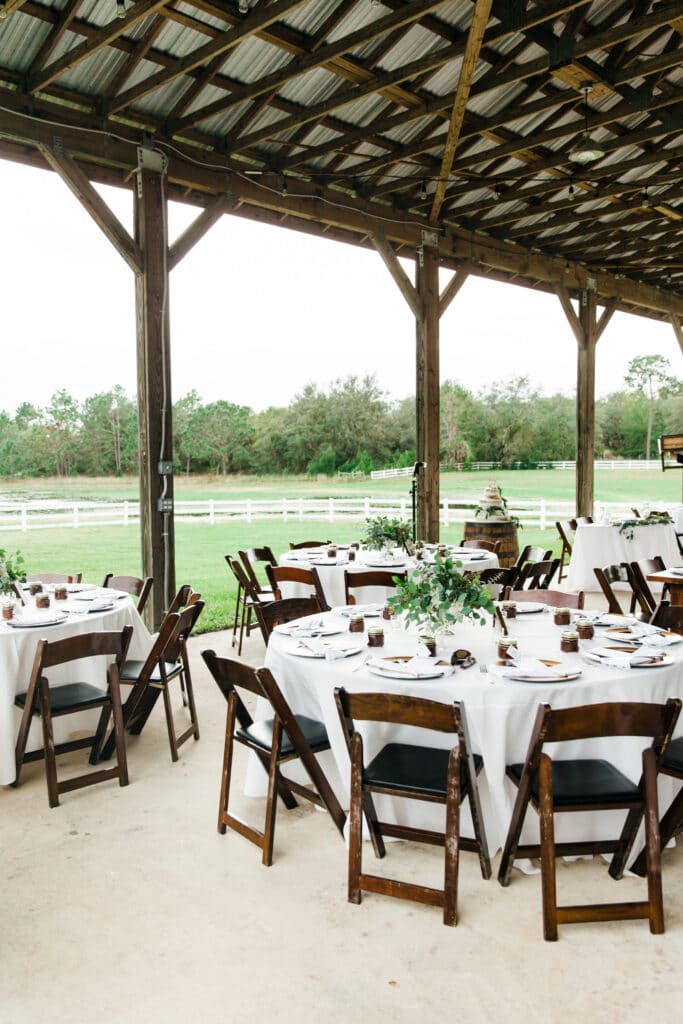 wedding reception at Bramble Tree Estate with white tablecloths and wooden chairs under large outdoor cover