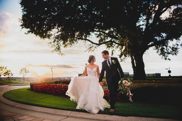 Bride and groom walking near a garden at sunset