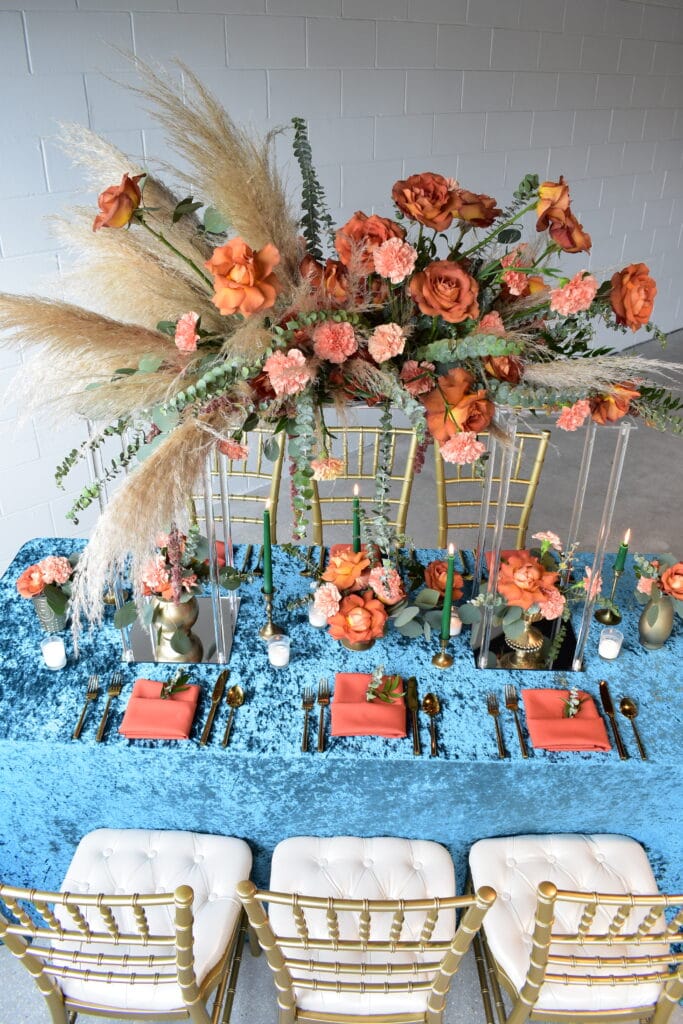 teal tablecloth and coral floral accents with grass fronts by Stems in Bloom