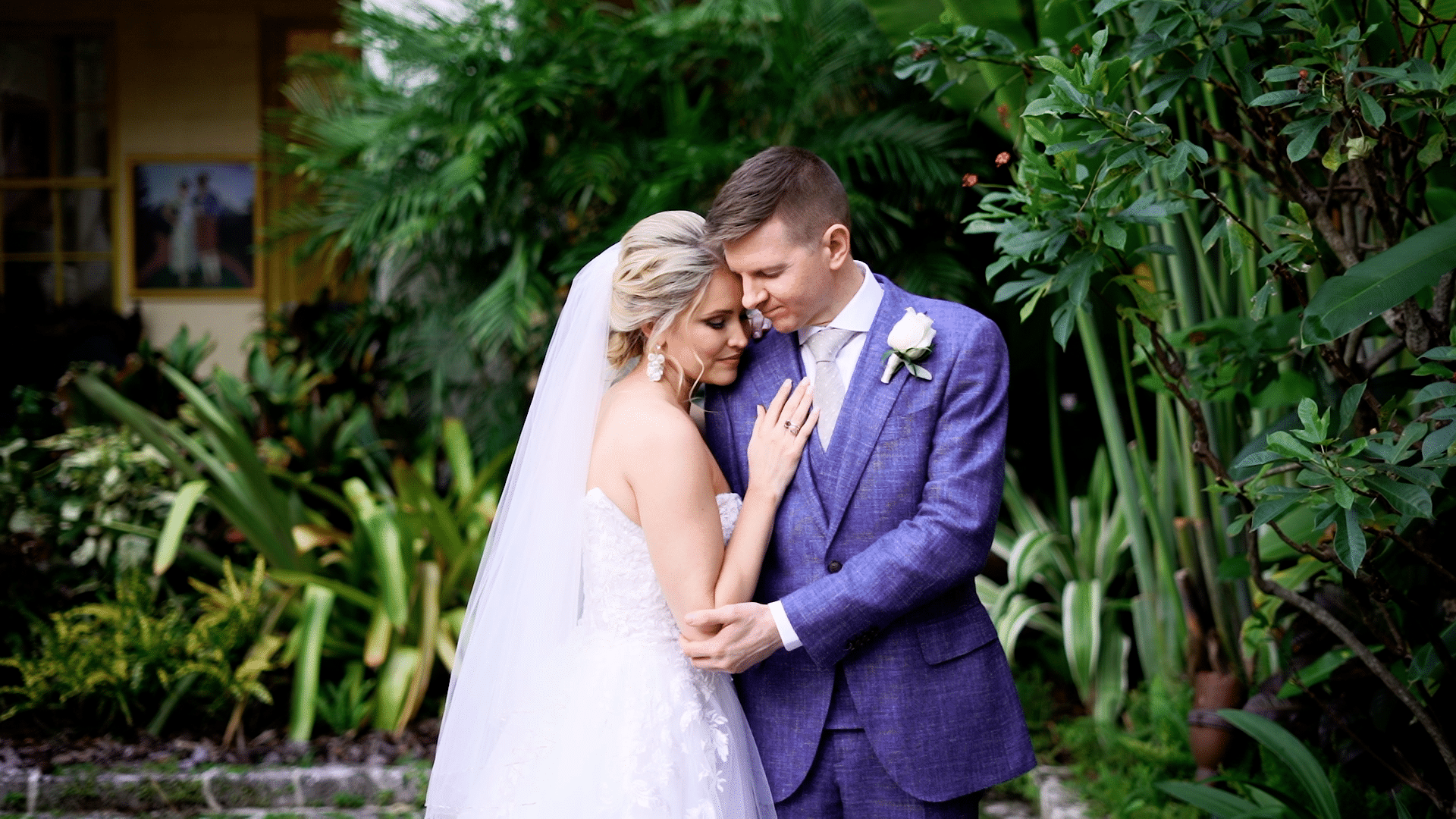 Bride and groom embracing in front of lush tropical plants