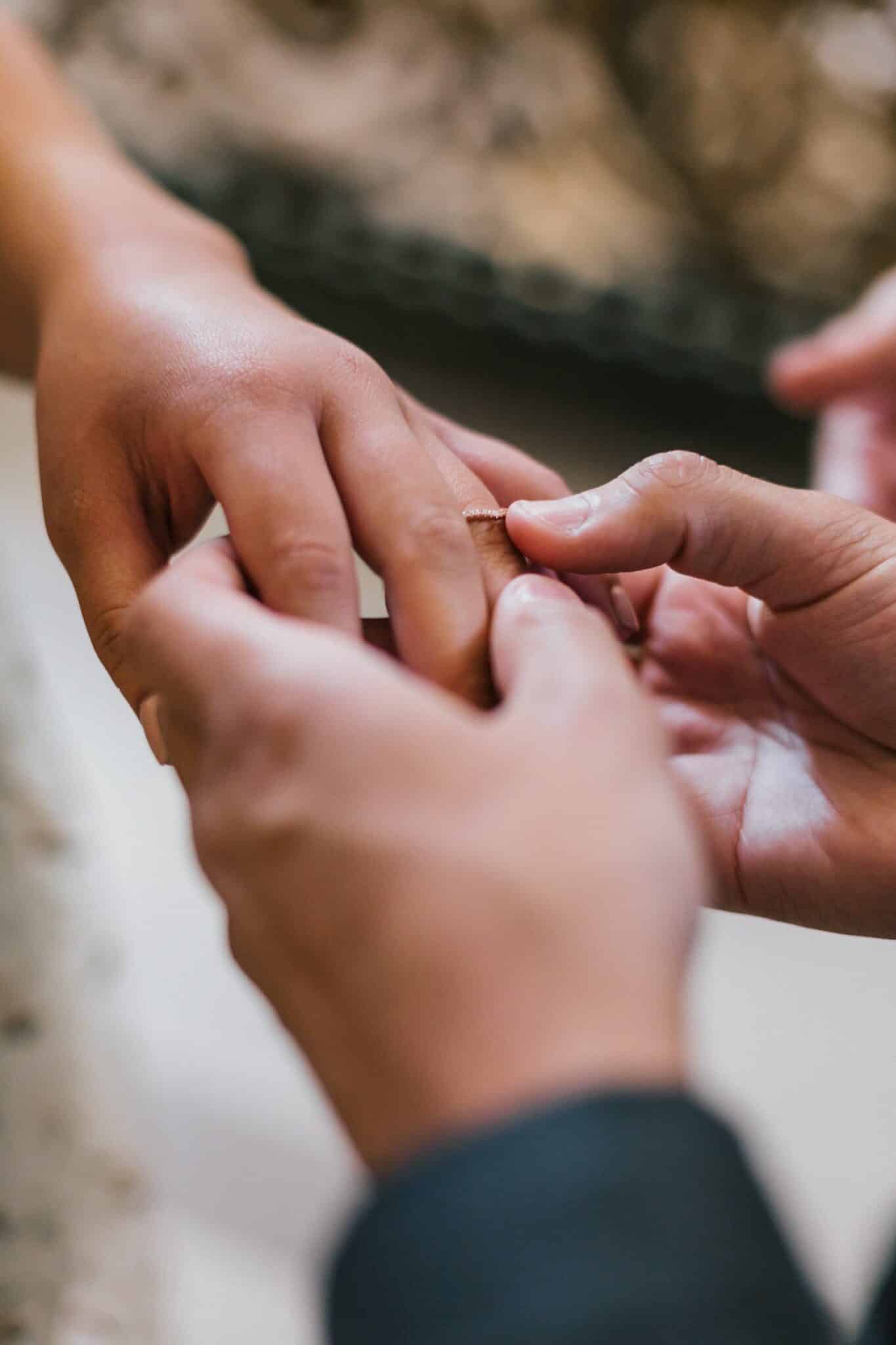groom sliding wedding ring onto brides ring finger