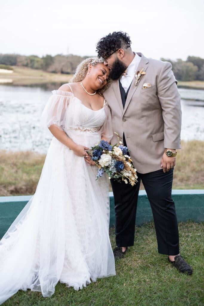grooms kissing top of bride's head at Camp Ithiel wedding on the water