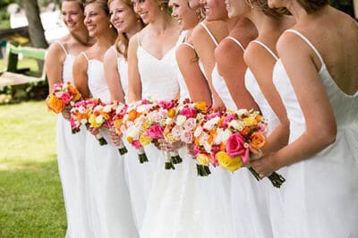bridesmaids in white with bouquets in multiple colors by Leaf & Blossom Co.