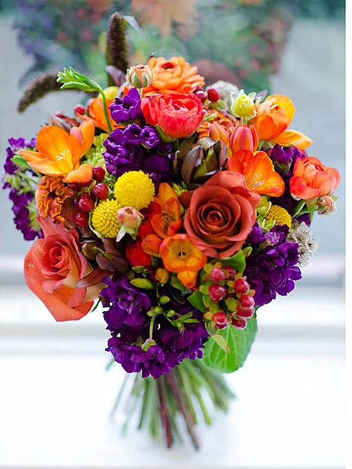 colorful table centerpiece in orange and purple flowers by Leaf & Blossom Co